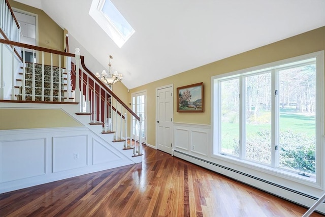foyer with stairway, lofted ceiling with skylight, a notable chandelier, and a baseboard radiator