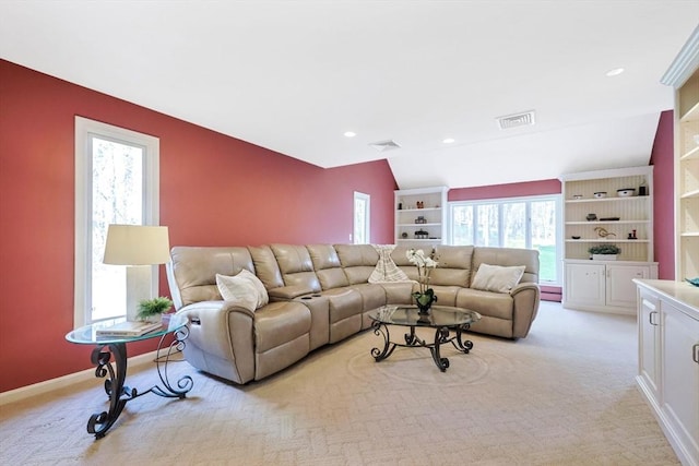 living area with baseboards, vaulted ceiling, visible vents, and light colored carpet