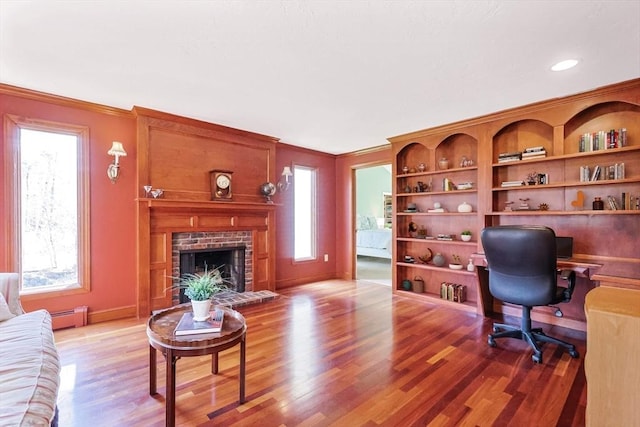 office featuring ornamental molding, light wood-type flooring, baseboards, a fireplace, and baseboard heating