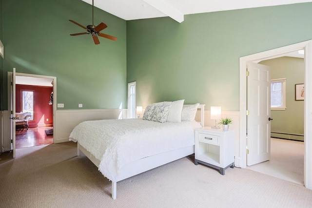 bedroom featuring a baseboard radiator, carpet flooring, high vaulted ceiling, and a wainscoted wall