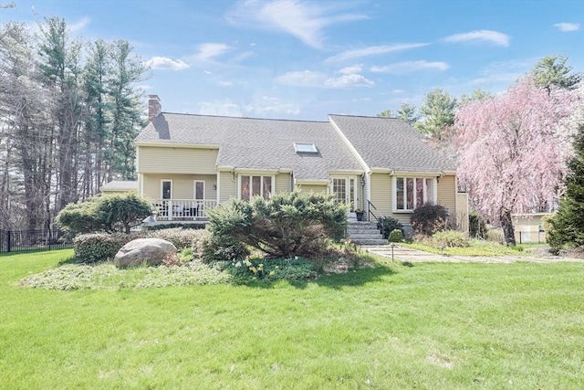 view of front of home featuring fence, a shingled roof, a front lawn, and a chimney