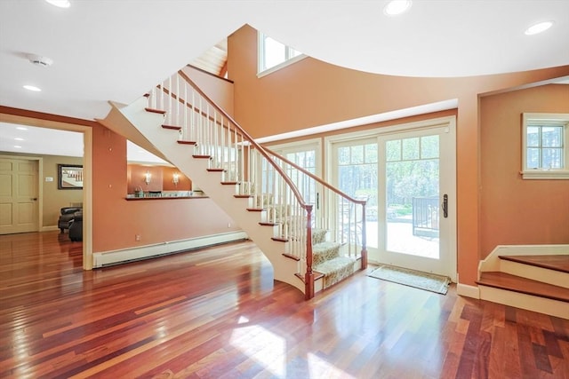 interior space featuring a baseboard heating unit, wood finished floors, and stairs