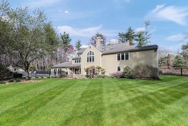 back of property featuring a lawn, a chimney, and fence