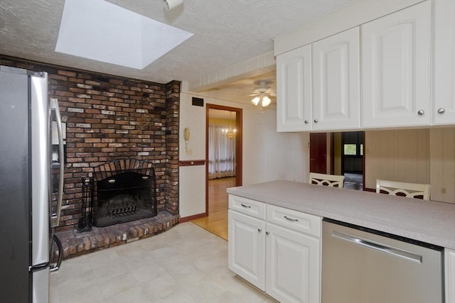 27 Chestnut Hill, South Hadley, MA 01075 - kitchen featuring appliances with stainless steel finishes, a textured ceiling, a fireplace, white cabinets, and a ceiling fan