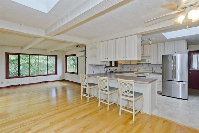 27 Chestnut Hill, South Hadley, MA 01075 - kitchen featuring white appliances, a skylight, a peninsula, white cabinets, and light wood finished floors