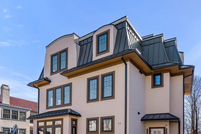 view of front of house with stucco siding, metal roof, and a standing seam roof