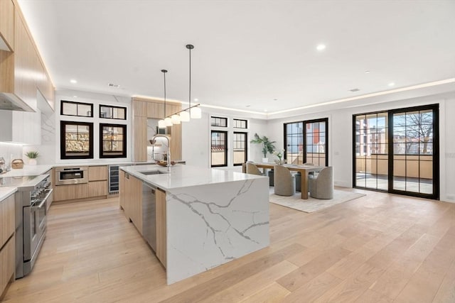 kitchen featuring stainless steel appliances, a sink, wine cooler, modern cabinets, and light wood-type flooring