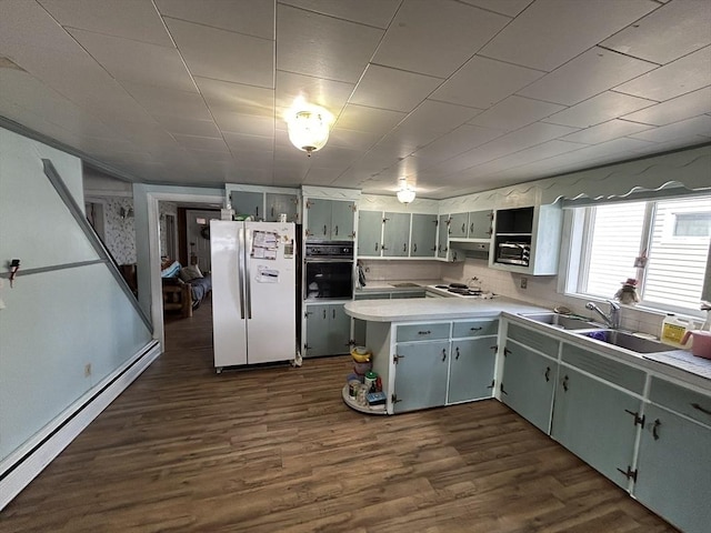 kitchen featuring open shelves, a baseboard radiator, freestanding refrigerator, oven, and a peninsula