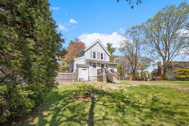 rear view of house with fence and a lawn
