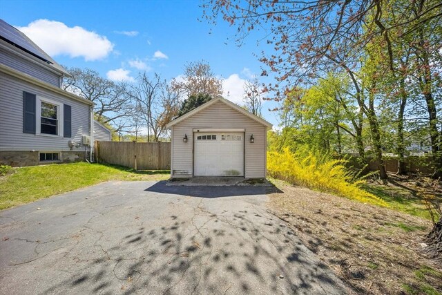 detached garage featuring fence and driveway