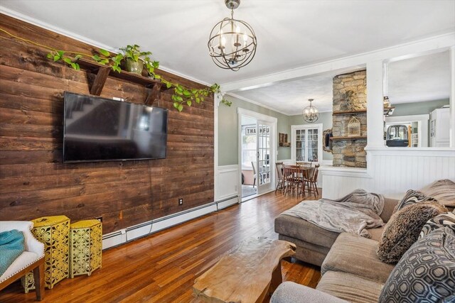 living area with an inviting chandelier, wainscoting, hardwood / wood-style floors, a baseboard heating unit, and ornamental molding