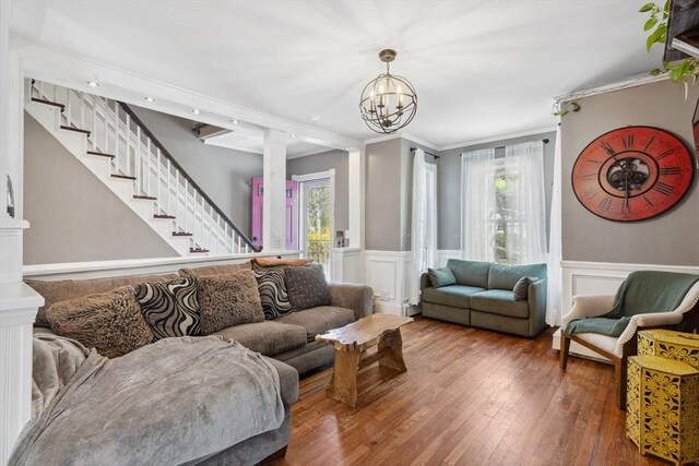 living area featuring wood-type flooring, stairs, a healthy amount of sunlight, and an inviting chandelier