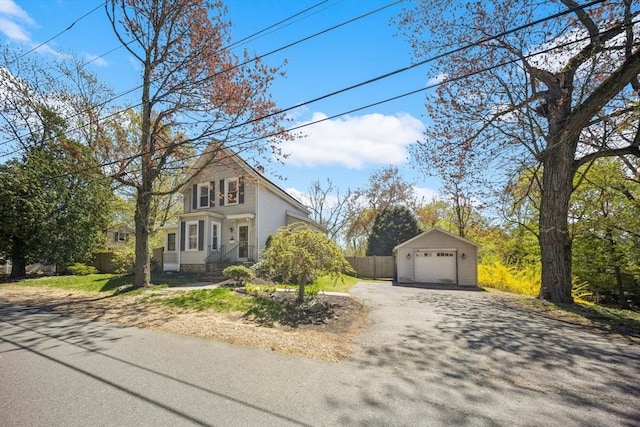 view of front of home with an outdoor structure, aphalt driveway, fence, and a detached garage