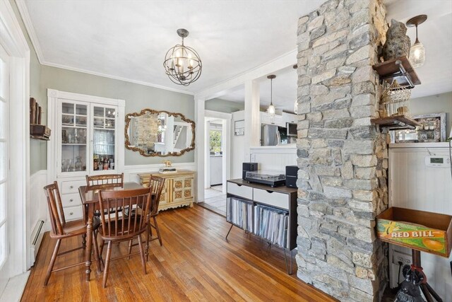 dining room with crown molding, baseboard heating, a chandelier, hardwood / wood-style floors, and washer / clothes dryer