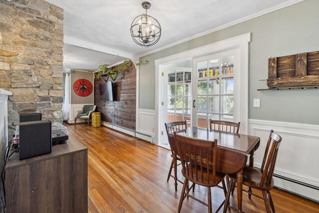 dining space featuring baseboard heating, wainscoting, wood finished floors, and a notable chandelier
