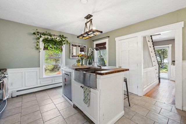 kitchen with a kitchen island with sink, baseboard heating, dishwasher, a sink, and wood counters