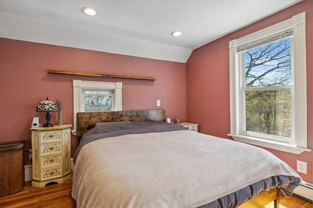bedroom with recessed lighting, wood finished floors, vaulted ceiling, and baseboard heating