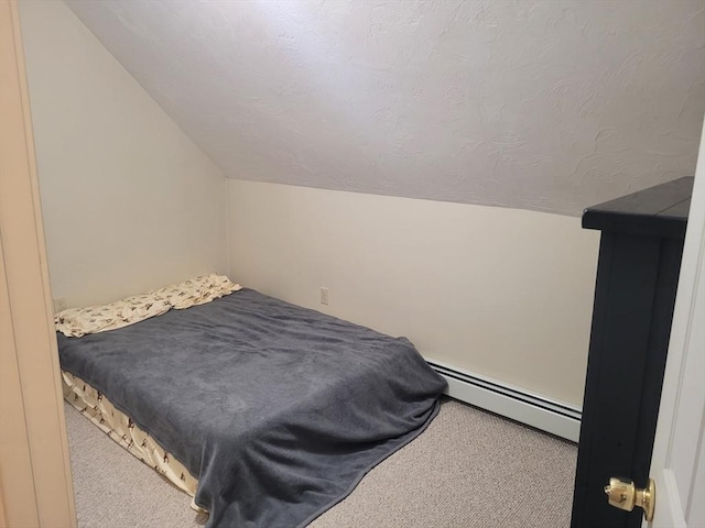 carpeted bedroom with vaulted ceiling and a baseboard heating unit