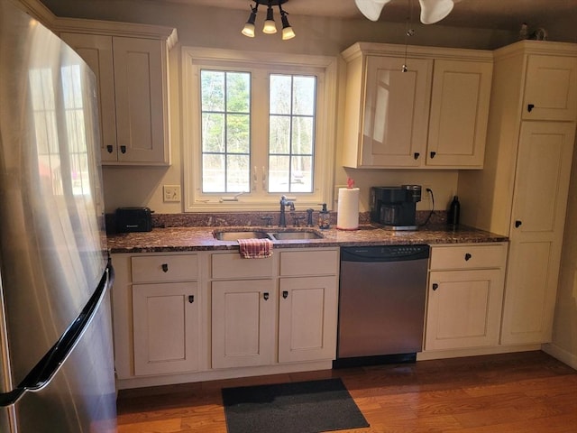 kitchen featuring white cabinetry, appliances with stainless steel finishes, sink, and dark stone counters