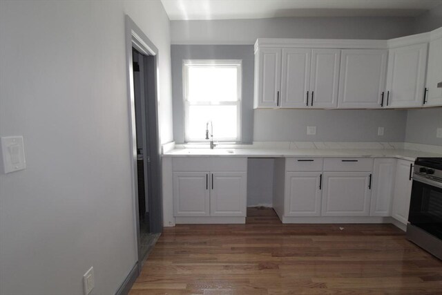 kitchen with stainless steel electric range oven, white cabinets, a sink, and light wood-style flooring
