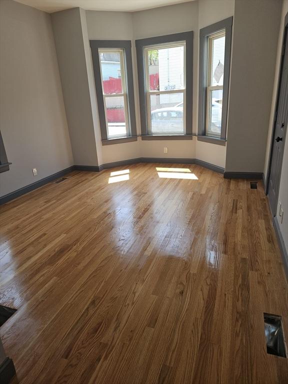 empty room with baseboards, wood finished floors, and visible vents