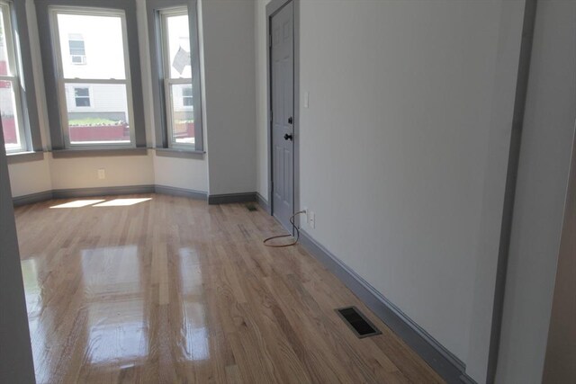 unfurnished room featuring baseboards, light wood finished floors, and visible vents
