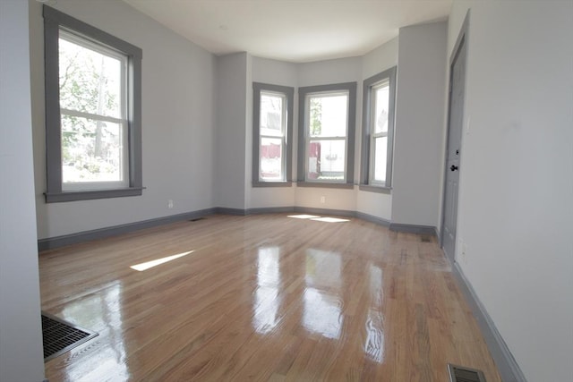 unfurnished room featuring baseboards, wood finished floors, and visible vents