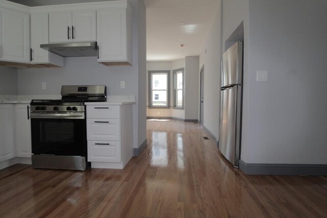 kitchen featuring baseboards, white cabinetry, under cabinet range hood, light wood-style flooring, and appliances with stainless steel finishes