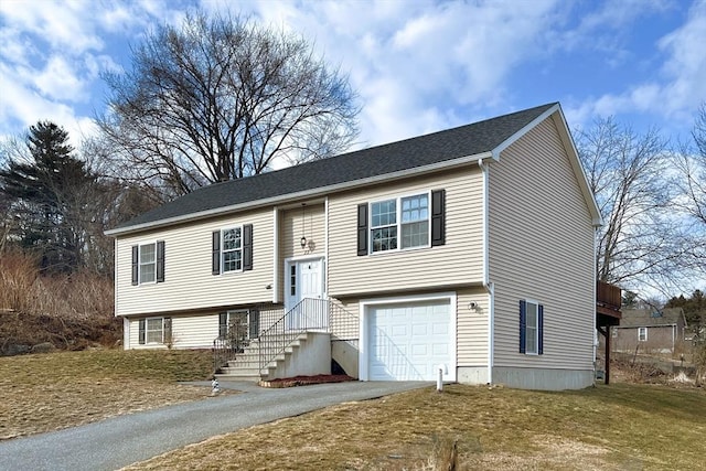 split foyer home with a garage, driveway, and a shingled roof