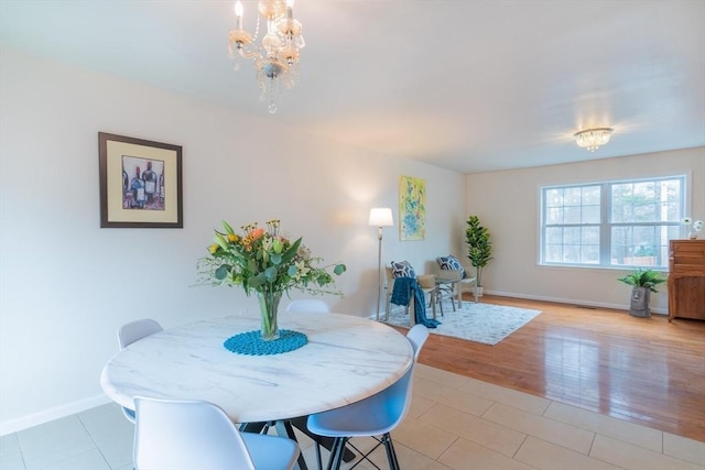 dining space with light wood-style floors, baseboards, and a notable chandelier