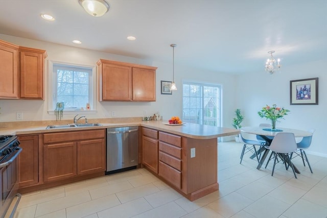 kitchen with gas stove, a peninsula, a sink, light countertops, and stainless steel dishwasher