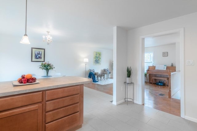 interior space with brown cabinets, a notable chandelier, pendant lighting, and light countertops