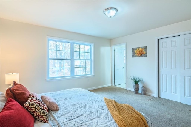 carpeted bedroom with a closet and baseboards