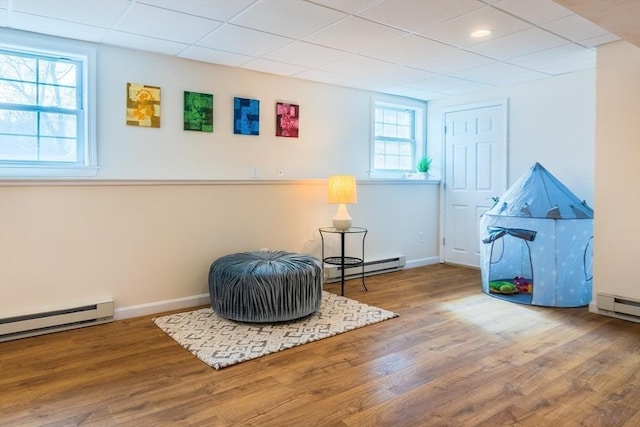 game room featuring wood finished floors, baseboards, and a baseboard radiator