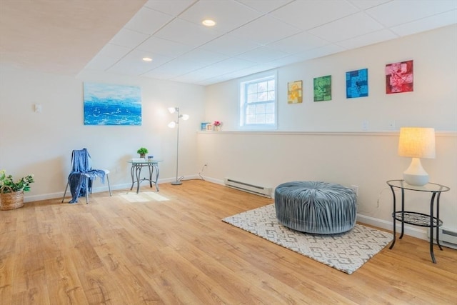 sitting room featuring a paneled ceiling, a baseboard heating unit, baseboards, and wood finished floors