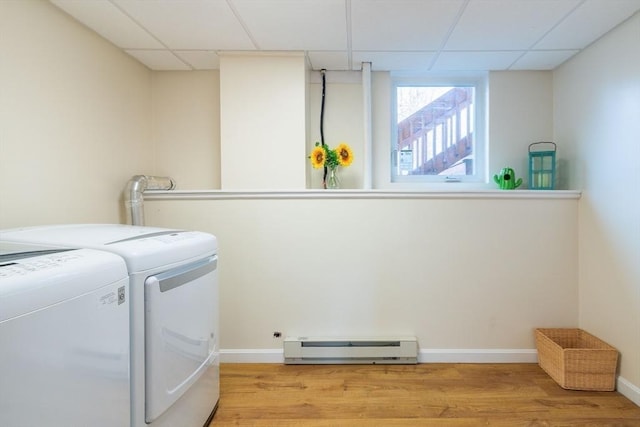 laundry area featuring a baseboard heating unit, baseboards, laundry area, light wood-style flooring, and washer and dryer