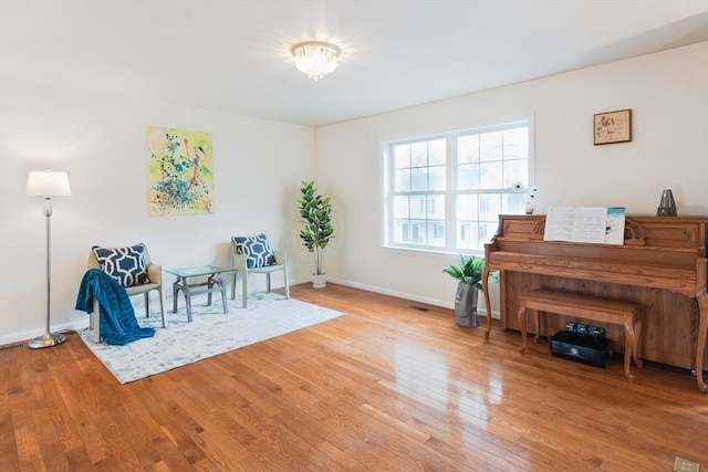 living area featuring visible vents, baseboards, and hardwood / wood-style flooring