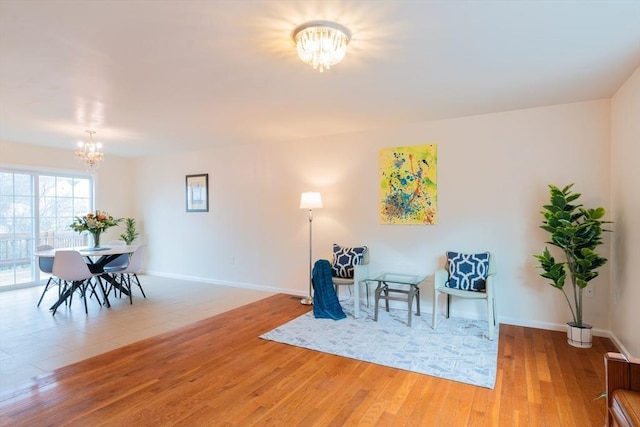 living area featuring a notable chandelier, wood finished floors, and baseboards