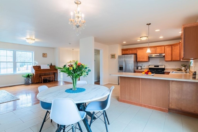 kitchen featuring under cabinet range hood, recessed lighting, stainless steel appliances, a peninsula, and light countertops