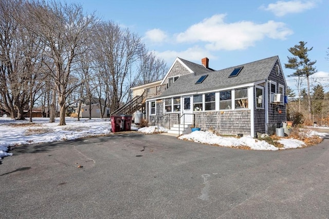 shingle-style home featuring a shingled roof, a chimney, and aphalt driveway