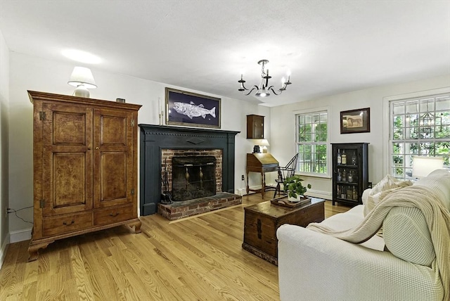 26 E St, Hopkinton, MA 01748 - living area with light wood-type flooring, a chandelier, a fireplace, and baseboards