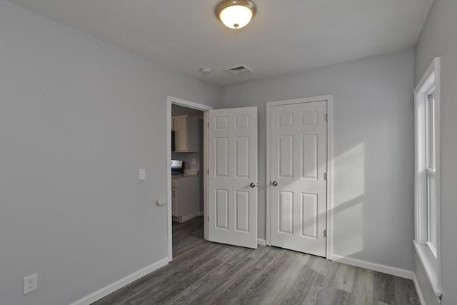 unfurnished bedroom with multiple windows, dark wood-type flooring, and a closet