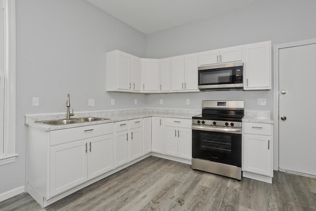 kitchen featuring sink, stainless steel appliances, light hardwood / wood-style floors, and white cabinets