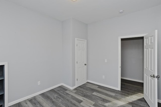 unfurnished bedroom featuring dark hardwood / wood-style flooring, a spacious closet, and a closet