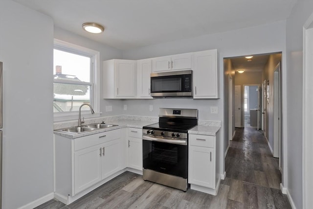 kitchen with stainless steel appliances, white cabinetry, and sink