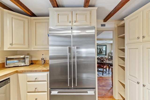 kitchen featuring stainless steel appliances, butcher block counters, beam ceiling, cream cabinetry, and light hardwood / wood-style floors