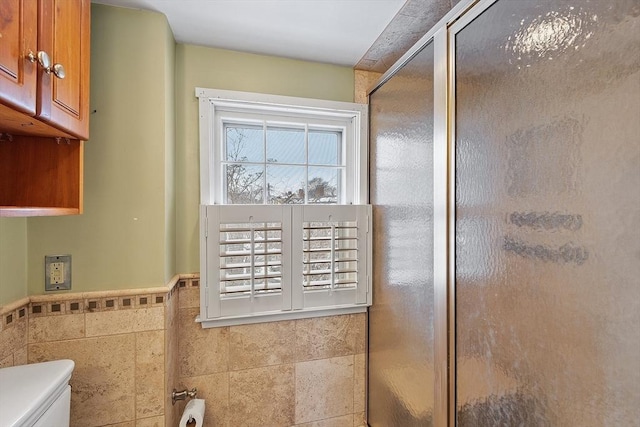 bathroom with tile walls, an enclosed shower, and toilet