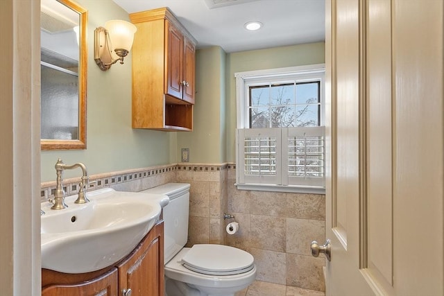 bathroom featuring toilet, tile patterned floors, tile walls, and vanity