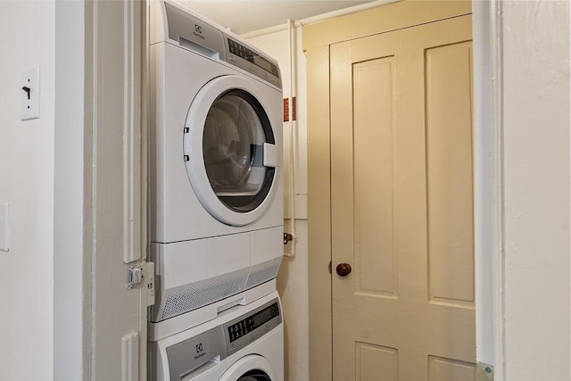 clothes washing area featuring stacked washing maching and dryer