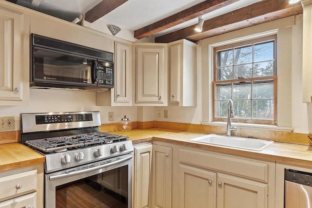 kitchen featuring wood counters, appliances with stainless steel finishes, sink, beamed ceiling, and cream cabinets